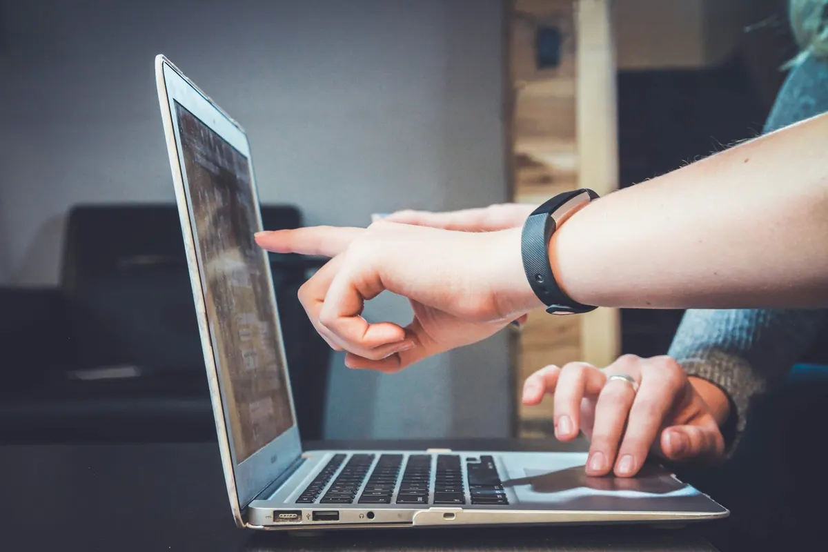 Two people pointing at a prototype on a laptop screen